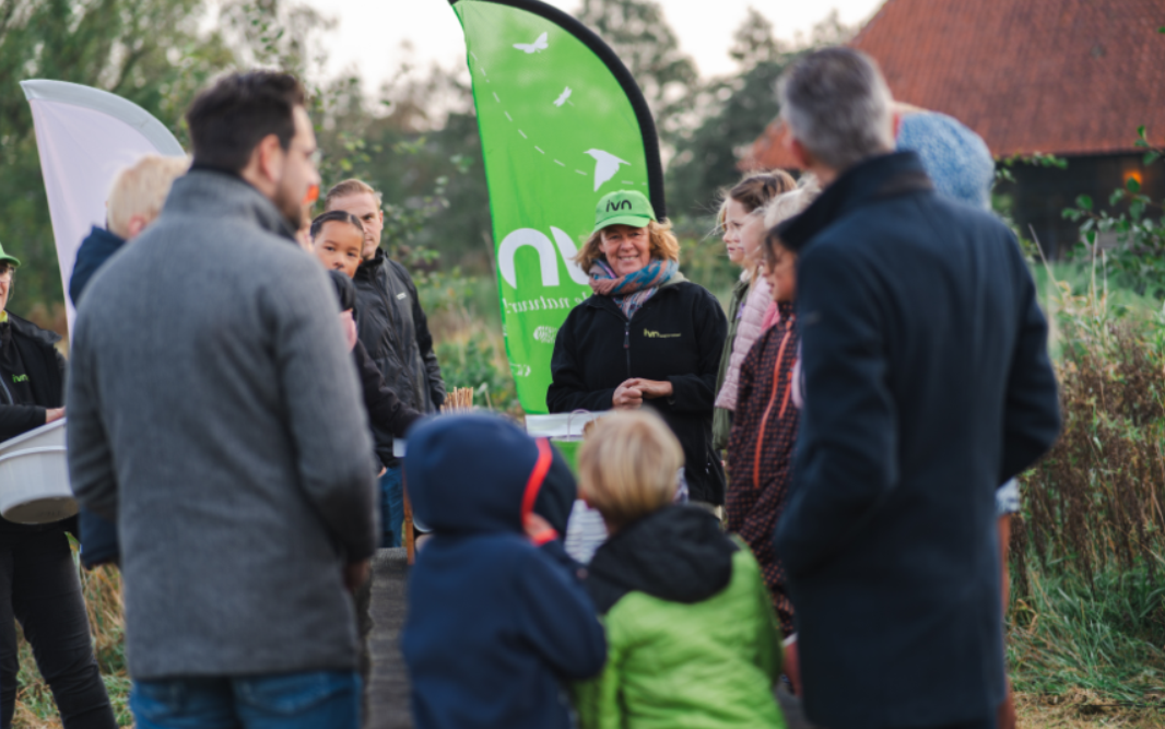 Wethouder Evert Stellingwerf en een aantal schoolkinderen krijgen uitleg over insecten en hun leefgebied.