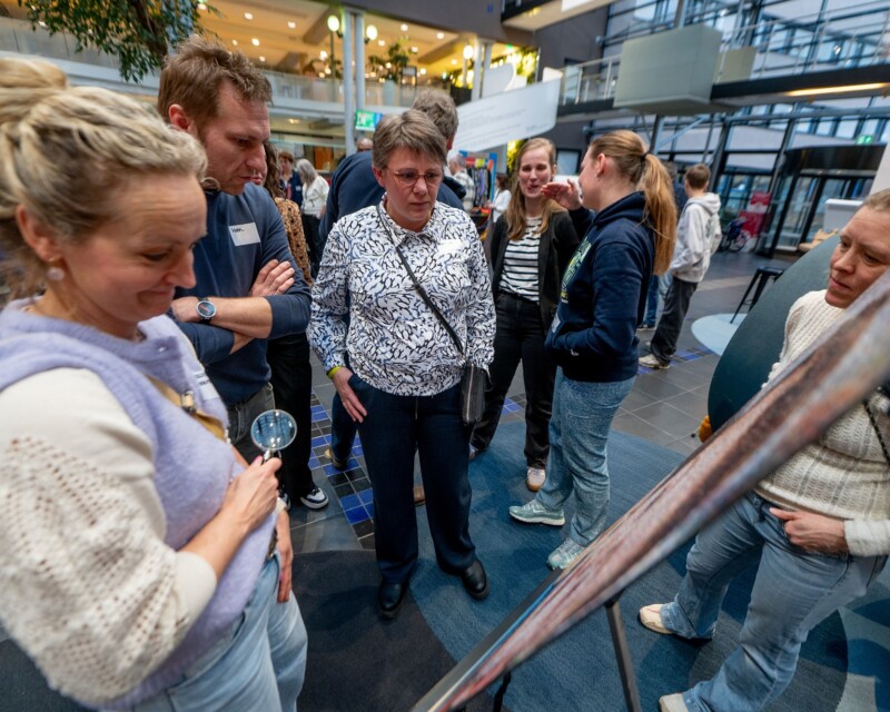 Wethouder Hein Kuiken bekijkt samen met enkele ouders een foto uit de expositie