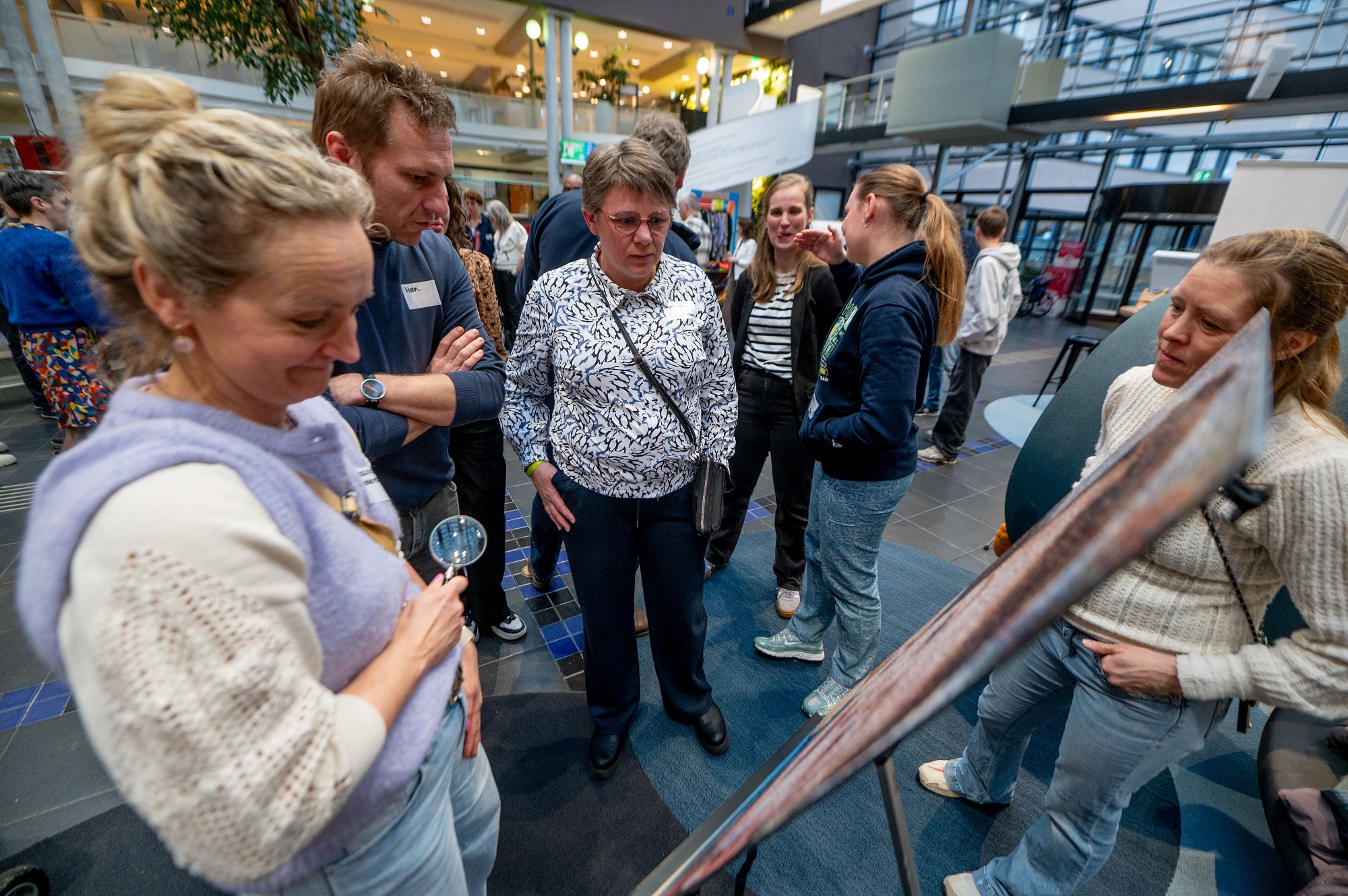 Wethouder Hein Kuiken bekijkt samen met enkele ouders een foto uit de expositie